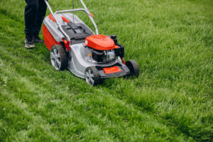 Lawn mower on healthy green lawn for natural lawn care in Richmond VA.