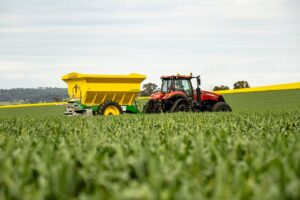 Tractor spreading grass seed across a green field for new lawn growth.