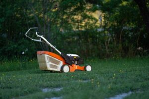 Orange lawn mower cutting grass for professional lawn care and landscape maintenance in Richmond VA.