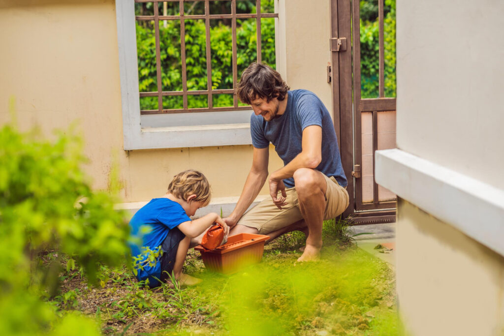 Father and child working in the yard to address soil and drainage issues near a home.