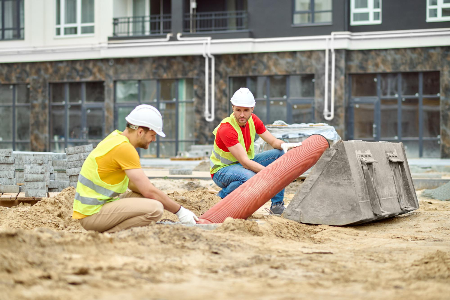 Excavation services Richmond VA with workers preparing underground drainage pipes at a residential construction site.